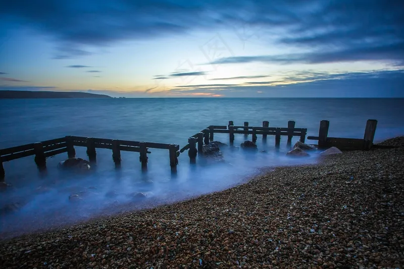暮色降临的海滩上孤旧的栈桥