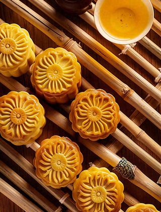 中国传统糕点月饼竹制托盘上的月饼中秋节木制背景摄影图
