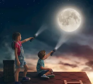 在屋顶用电筒指着月亮图片