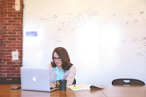 在会议室的茶杯笔记本电脑上工作的眼镜的女人 在会议室的茶杯笔记本电脑上工作的眼镜的女人