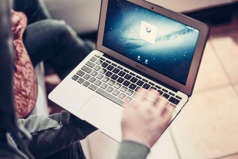 坐在客厅里，笔记本电脑上工作的人