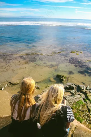 坐在岩石顶部，看着视图的两个女性朋友