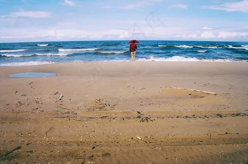 伞站在海滩上,看着大海的人 伞站在海滩上,看着大海的人