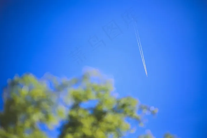 客运飞机在湛蓝的天空中高飞，留下长长的白色足迹