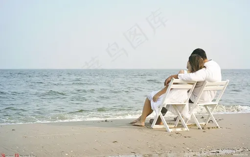 拥抱在海滩上,看着大海的年轻夫妇 拥抱在海滩上,看着大海的年轻夫妇